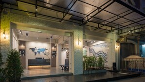 A modern hotel lobby with a reception desk, seating area, and decorative wall art. - Natee Hostel (Bangkok)