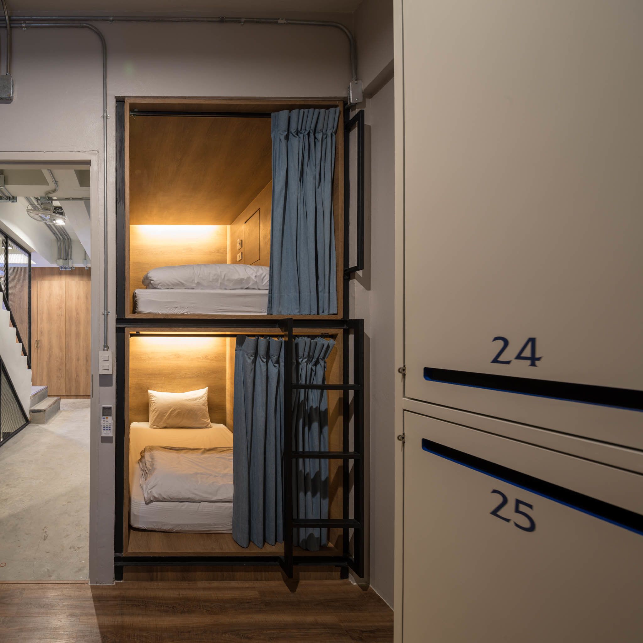 A compact hotel room with bunk beds, a control panel, and a staircase leading to another room.