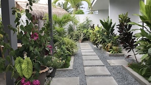A garden pathway with potted plants and a thatched-roof structure. - Royal Stay Inn (Thoddoo)