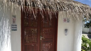 A wooden door with vertical slats, a thatched roof, and a wall-mounted intercom. - Royal Stay Inn (Thoddoo)