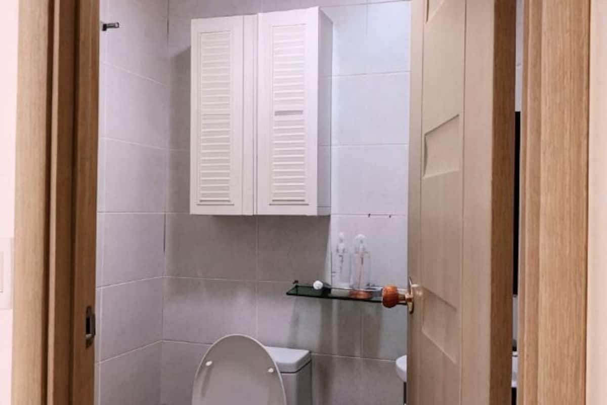 Un baño con inodoro, lavamanos y un mueble sobre el espejo.