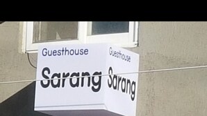 A sign for 'Guesthouse Sarang Sarang' with a window in the background.