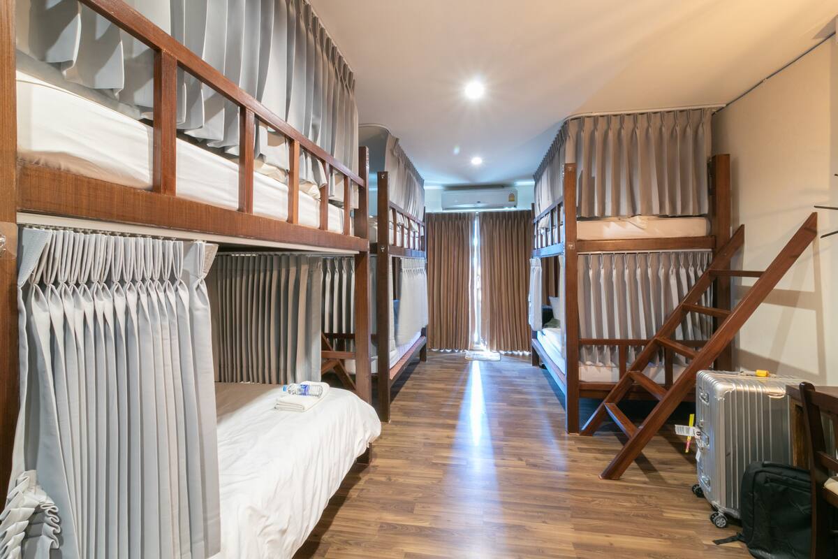 A room with bunk beds, a wooden ladder, a suitcase, and a radiator.