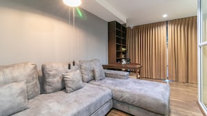 A modern living room with a sectional sofa, a wooden coffee table, and a built-in shelving unit. - Phobphanhostel (Bangkok)