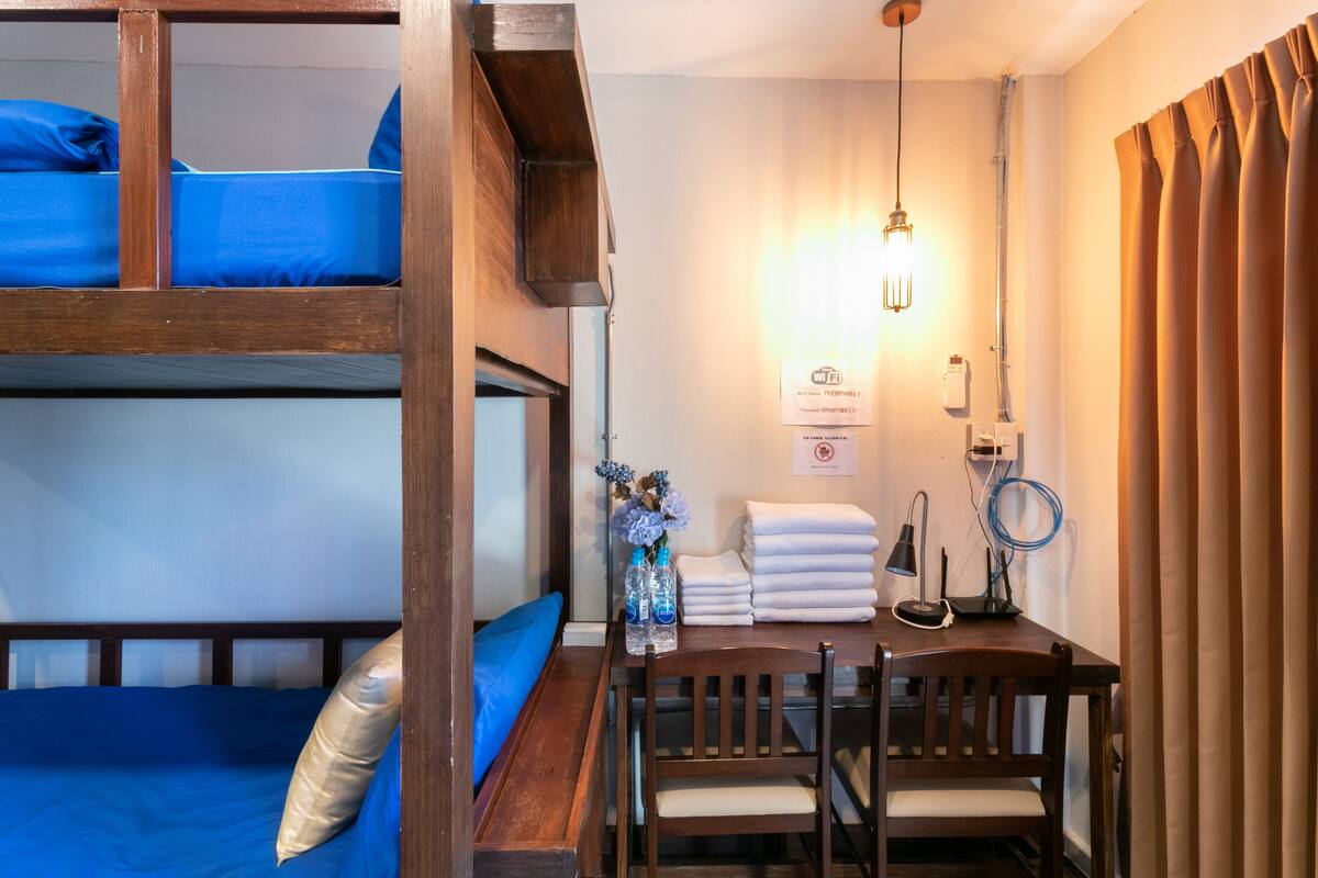 A bunk bed room with a desk, chair, and a hanging light fixture.