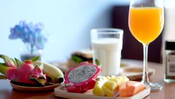 Una colazione con un piatto di pitahaya, mango e salmone, un bicchiere di succo d'arancia e un bicchiere di latte.