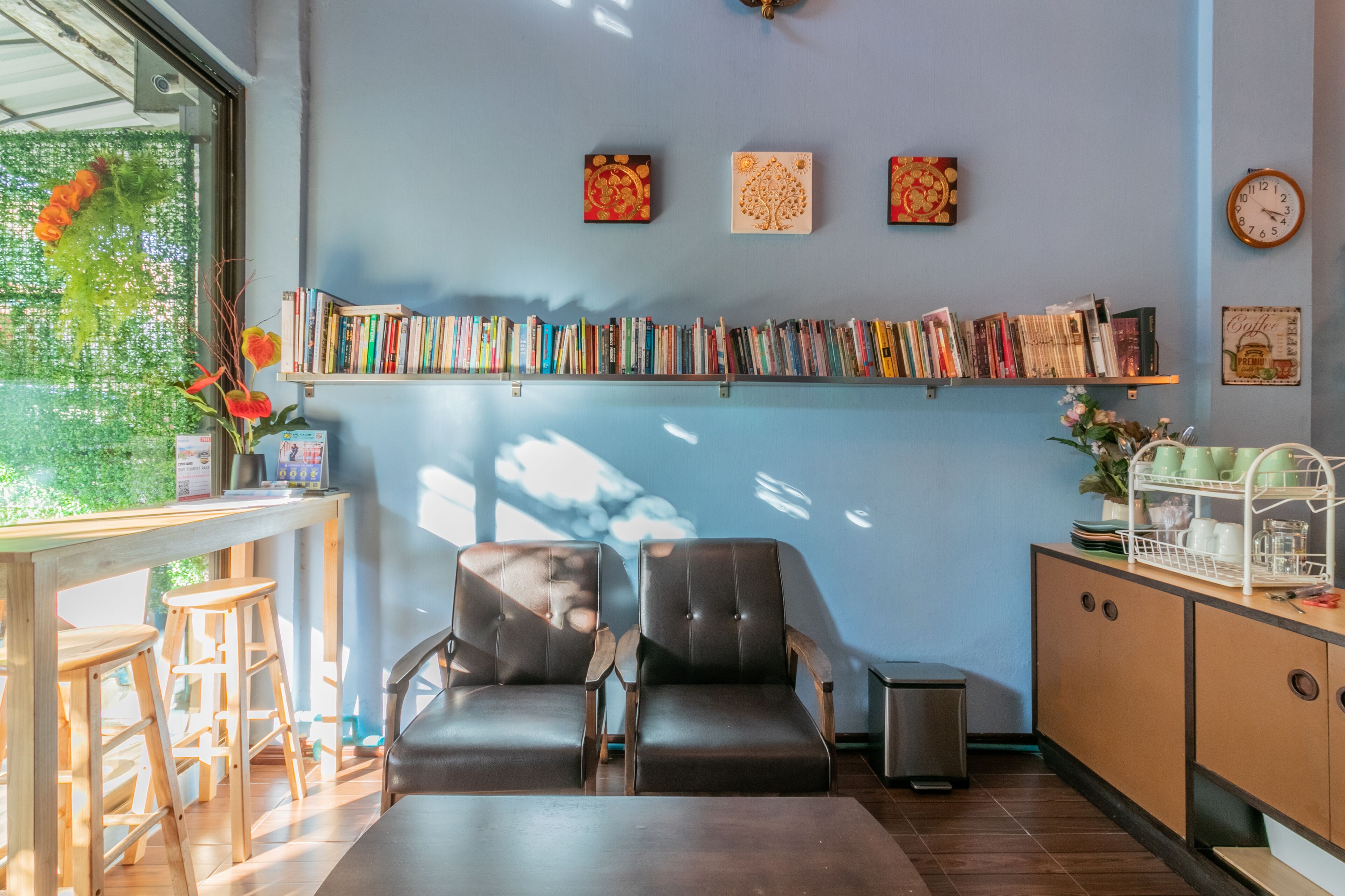 Un rincón acogedor para leer con una estantería, dos sillones de cuero, una mesita y una estación para café.