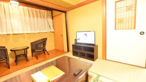 A traditional Japanese room with tatami flooring, a low wooden table, a television, and a sliding door with a decorative grid pattern. - Matoba biru (Osaka)