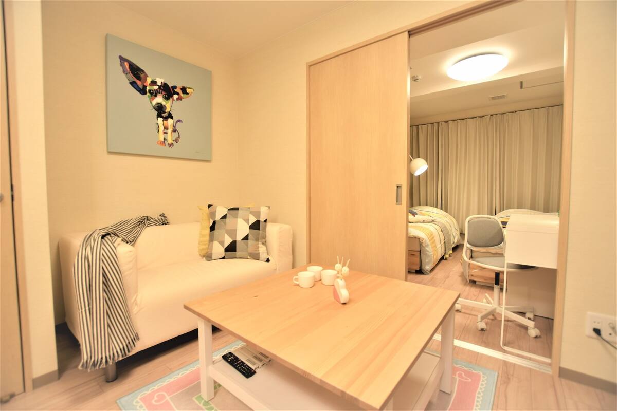 Ein modernes Hotelzimmer mit einem Holztisch, einer Couch mit gestreifter Decke, einem Bild eines Hundes und einem Schreibtisch mit Stuhl.