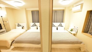 A mirrored view of a hotel room with two beds, a bedside table with a lamp, a window with curtains, and a wall-mounted air conditioner. - Matoba biru (Osaka)