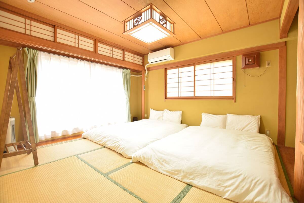 Ein traditioneller japanischer Raum mit Tatami-Bodenbelag, zwei Betten, einer Leiter und Shoji-Schiebetüren.
