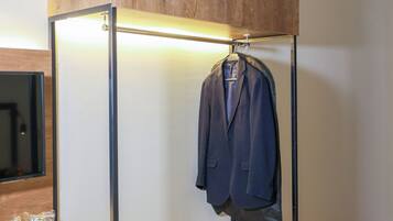Una habitación compacta con un armario de madera, un escritorio con ordenador y un perchero.