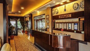 A reception area with a reception desk, a clock, and a restaurant sign.