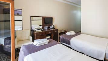 Habitación de hotel con dos camas, un escritorio con televisor, una silla y un espejo.