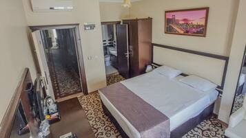 A hotel room with a bed, a desk, a wardrobe, and a bathroom visible through an open door.