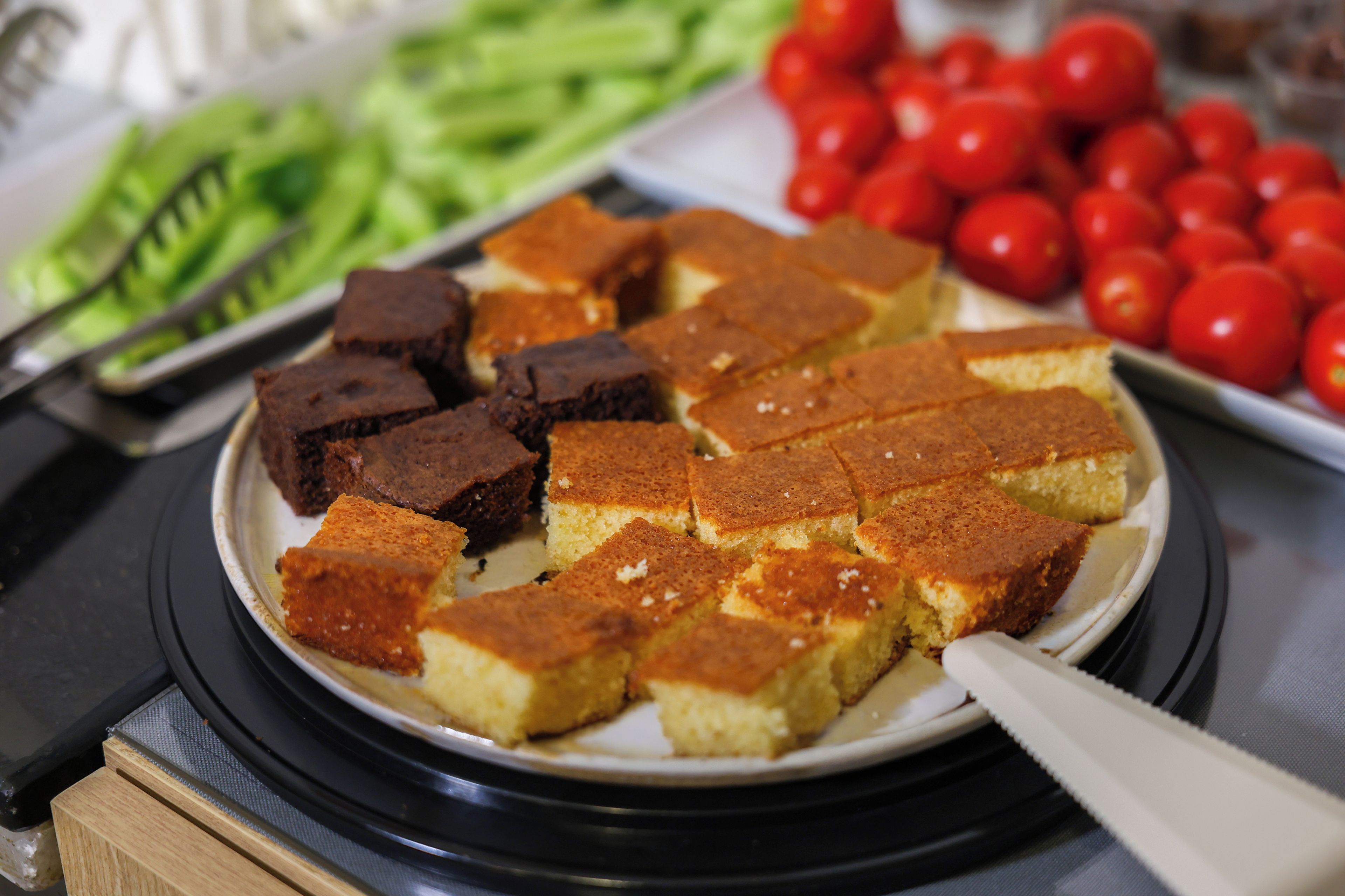 Ein Teller mit Speisen, darunter Brownies und eine Schale mit Cocktailtomaten.
