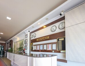 A reception area with a reception desk, clocks, and framed certificates on the wall. - Teona Hotel (Izmit)