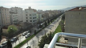 A residential street with multi-story buildings, a clear road, and a distant view of hills.