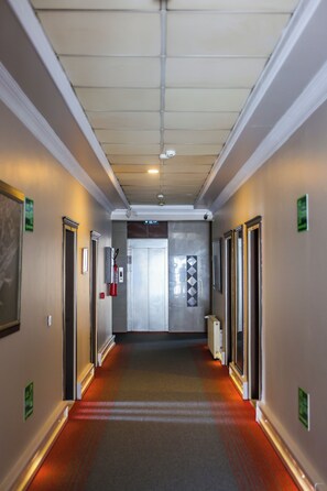 A hotel corridor with doors on both sides, a fire extinguisher, and an exit sign. - Teona Hotel (Izmit)