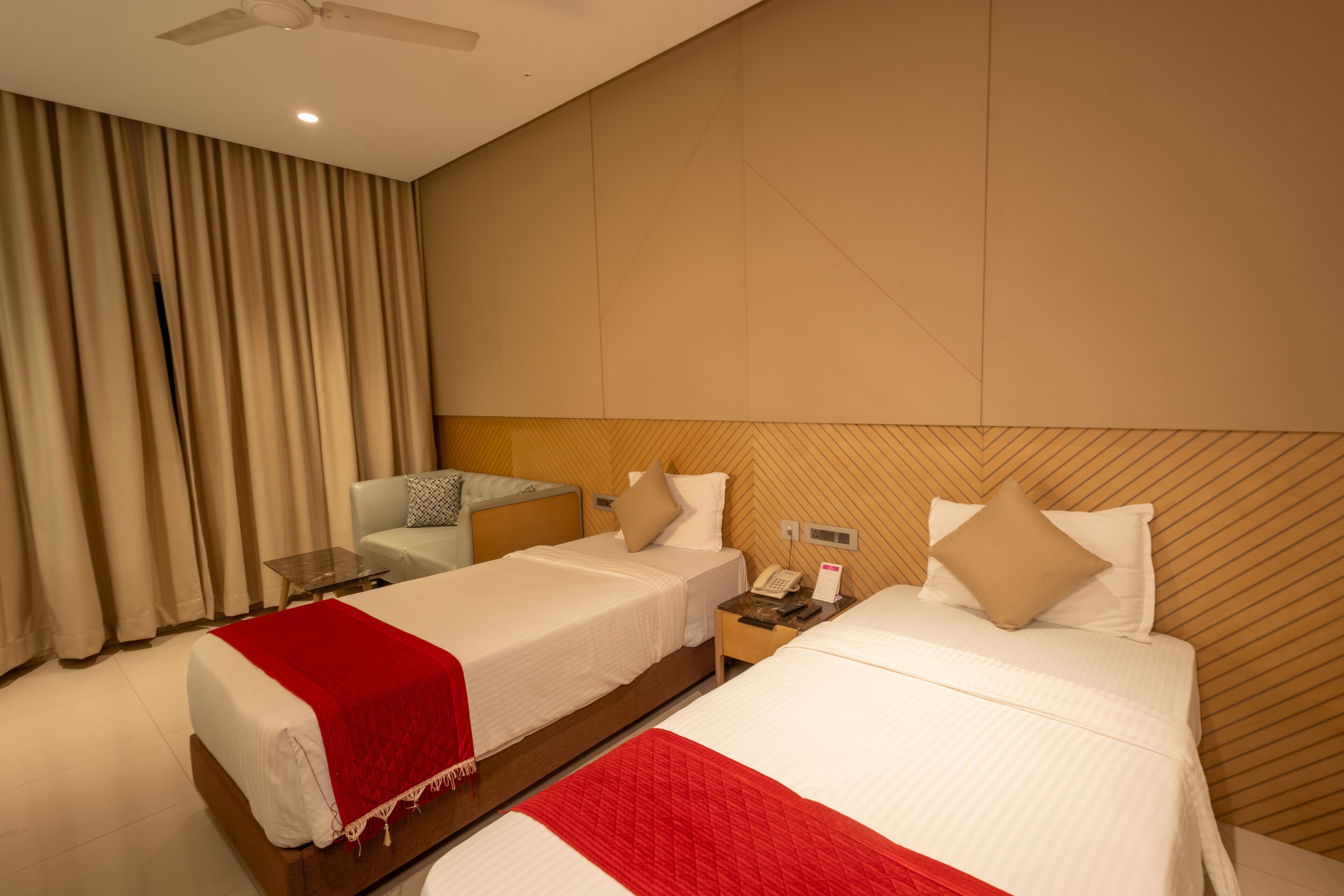 Una habitación de hotel con dos camas, una mesita de noche con un teléfono y un ventilador de techo.