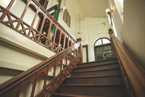 A wooden staircase with ornate railings and a view of a green door at the top. - 501 Merchant Bed & Breakfast - Hostel (Yangon)
