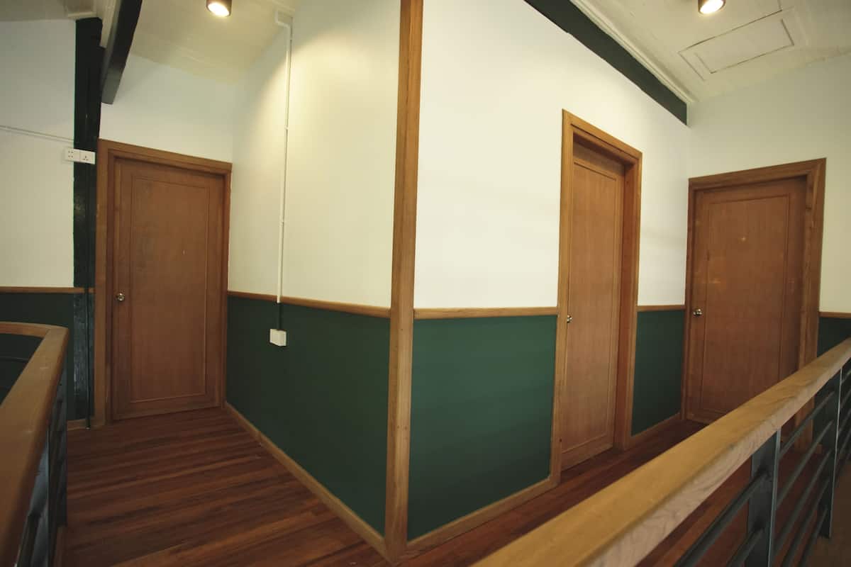 A hallway with wooden doors, green walls, and a wooden floor.