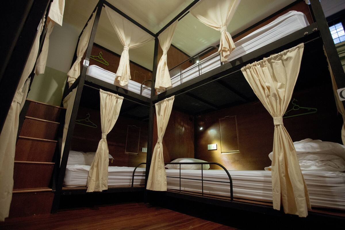 A bunk bed room with curtains, wooden walls, and a small table.