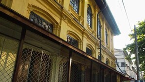A yellow building with a metal fence in front. - 501 Merchant Bed & Breakfast - Hostel (Yangon)