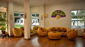 A spacious lobby with wooden flooring, a large window, and a seating area with yellow chairs. - Immana Grand Inle Hotel (Nyaungshwe)