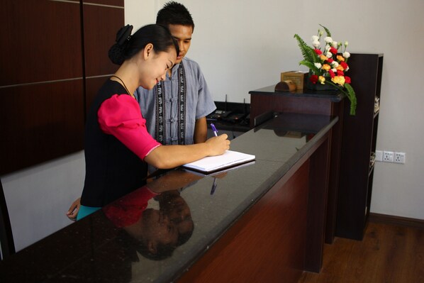 Un mostrador de recepción con un bloc de notas, un bolígrafo y un arreglo floral.
