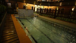 An indoor swimming pool with a wooden deck, metal railings, and a water feature. - Immana Grand Inle Hotel (Nyaungshwe)