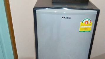 Un refrigerador compacto con el logotipo de Mitsubishi, un adhesivo que indica una garantía de 5 años y un dispensador de agua en la parte superior.