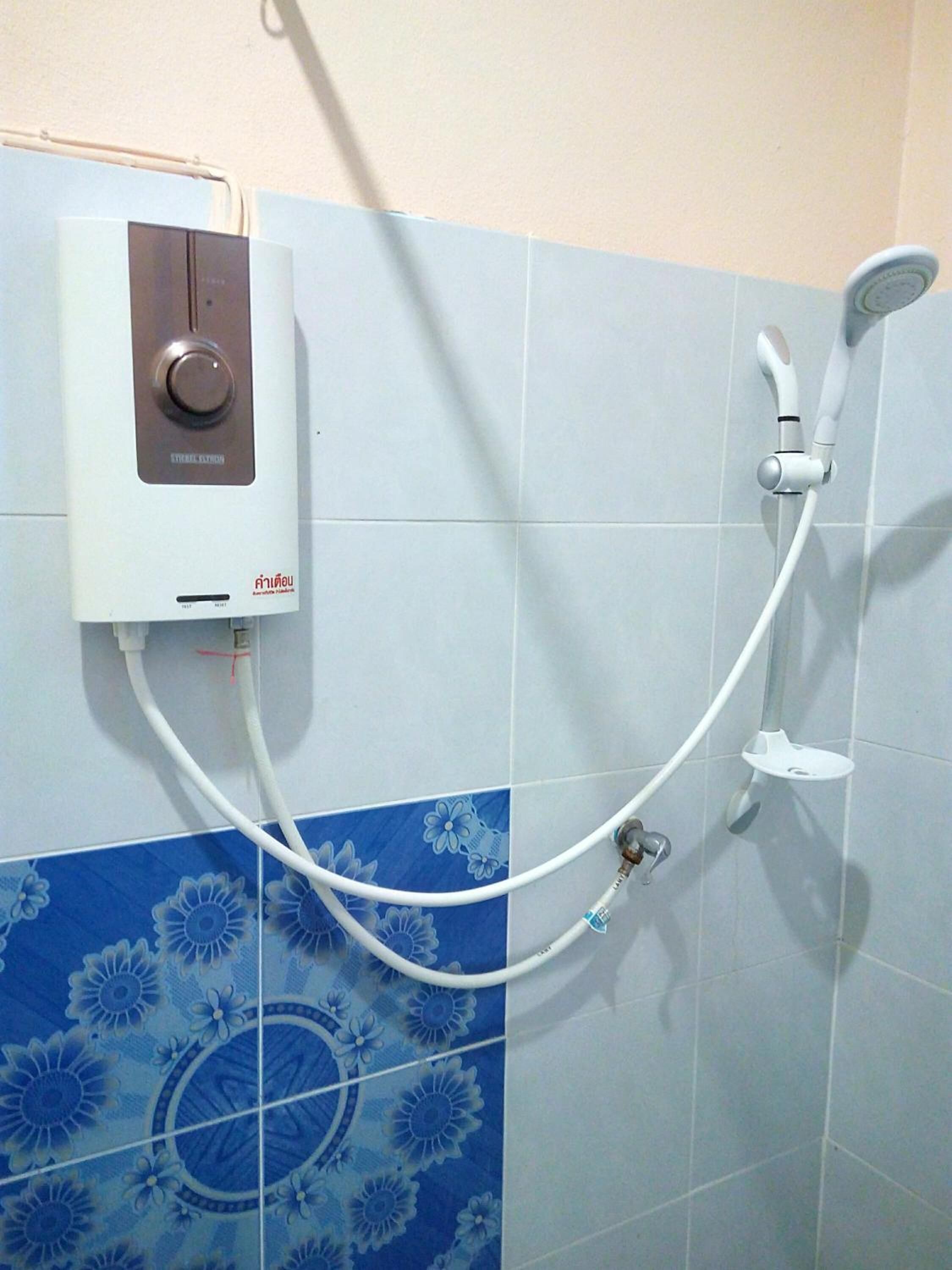 Une salle de bain équipée d’une douche murale, d’un pommeau de douche à main et d’un robinet.