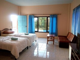 Quarto de hotel com duas camas, uma mesa pequena, um sofá de couro marrom e uma televisão.