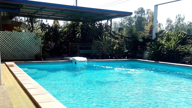 A swimming pool with a tiled edge, a rubberized safety strip, and a covered area with a roof. - Peace Pool Resort (Khun Han)