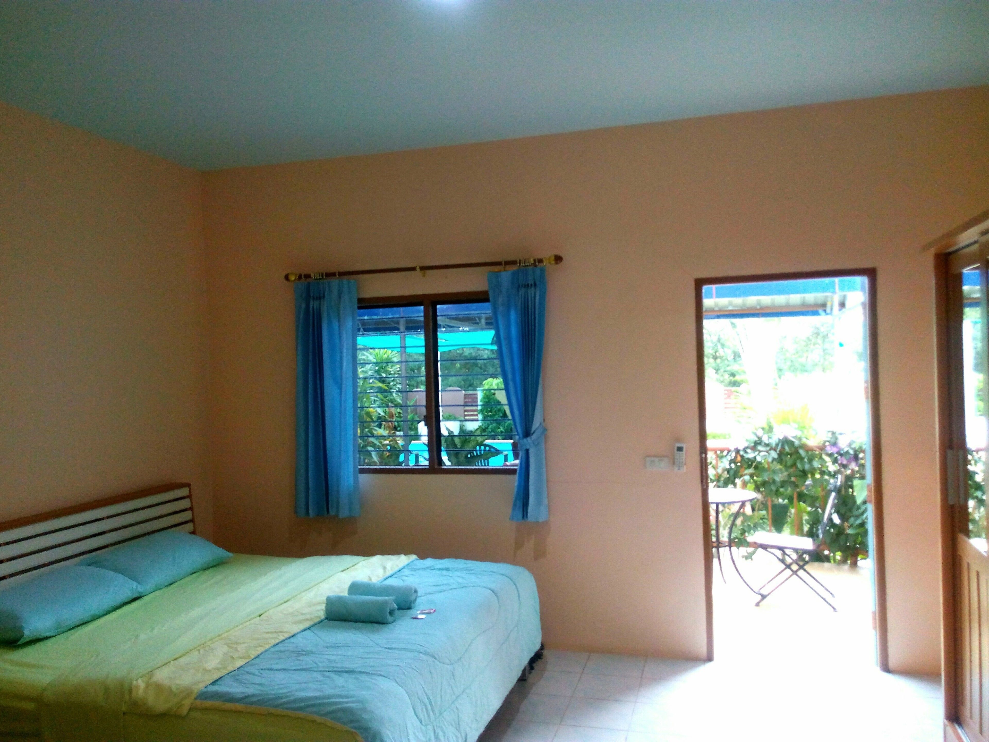 A bedroom with a bed, a window with curtains, and a view of the outside.