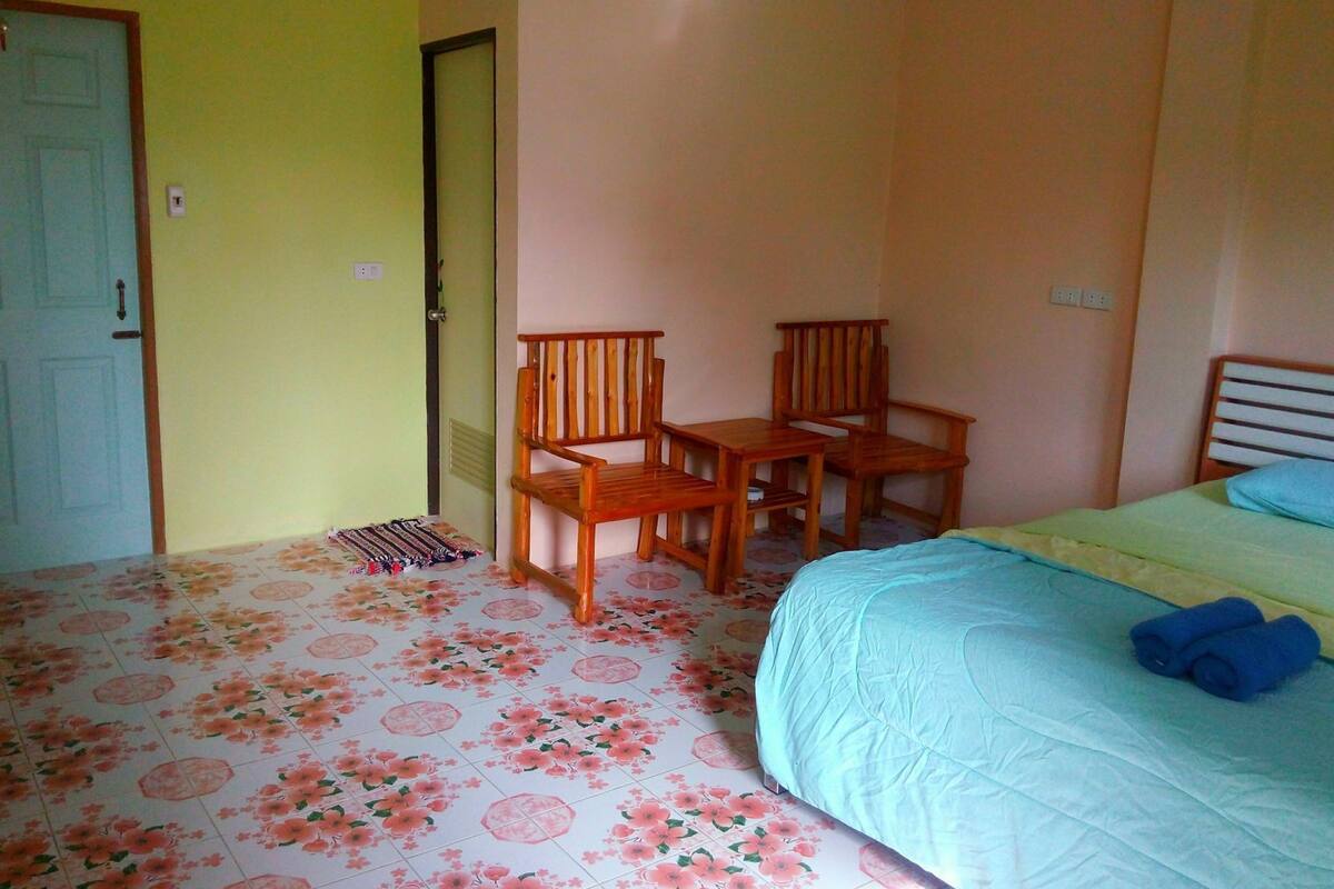 Ein Schlafzimmer mit einem Bett, zwei Holzstühlen, einem kleinen Tisch und einer Tür.