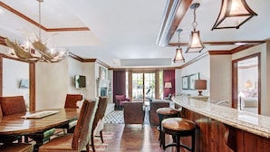 A spacious hotel lobby with a wooden floor, a bar area with stools, and a fireplace. - Exclusive 2BR Ritz-Carlton w Mountain Rustic Décor by RedAwning - Save 20% on 7+ Nights! (Vail)
