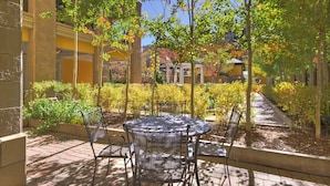 An outdoor patio with a round metal table and chairs, surrounded by greenery and a pathway. - Exclusive 2BR Ritz-Carlton w Mountain Rustic Décor by RedAwning - Save 20% on 7+ Nights! (Vail)