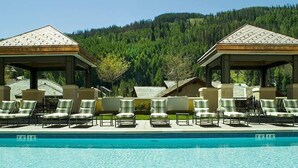 A pool area with lounge chairs and gazebos, surrounded by a forested hillside. - Exclusive 2BR Ritz-Carlton w Mountain Rustic Décor by RedAwning - Save 20% on 7+ Nights! (Vail)