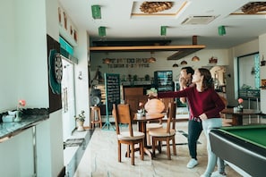 A billiards table, a dartboard, and a menu board in a cafe setting.