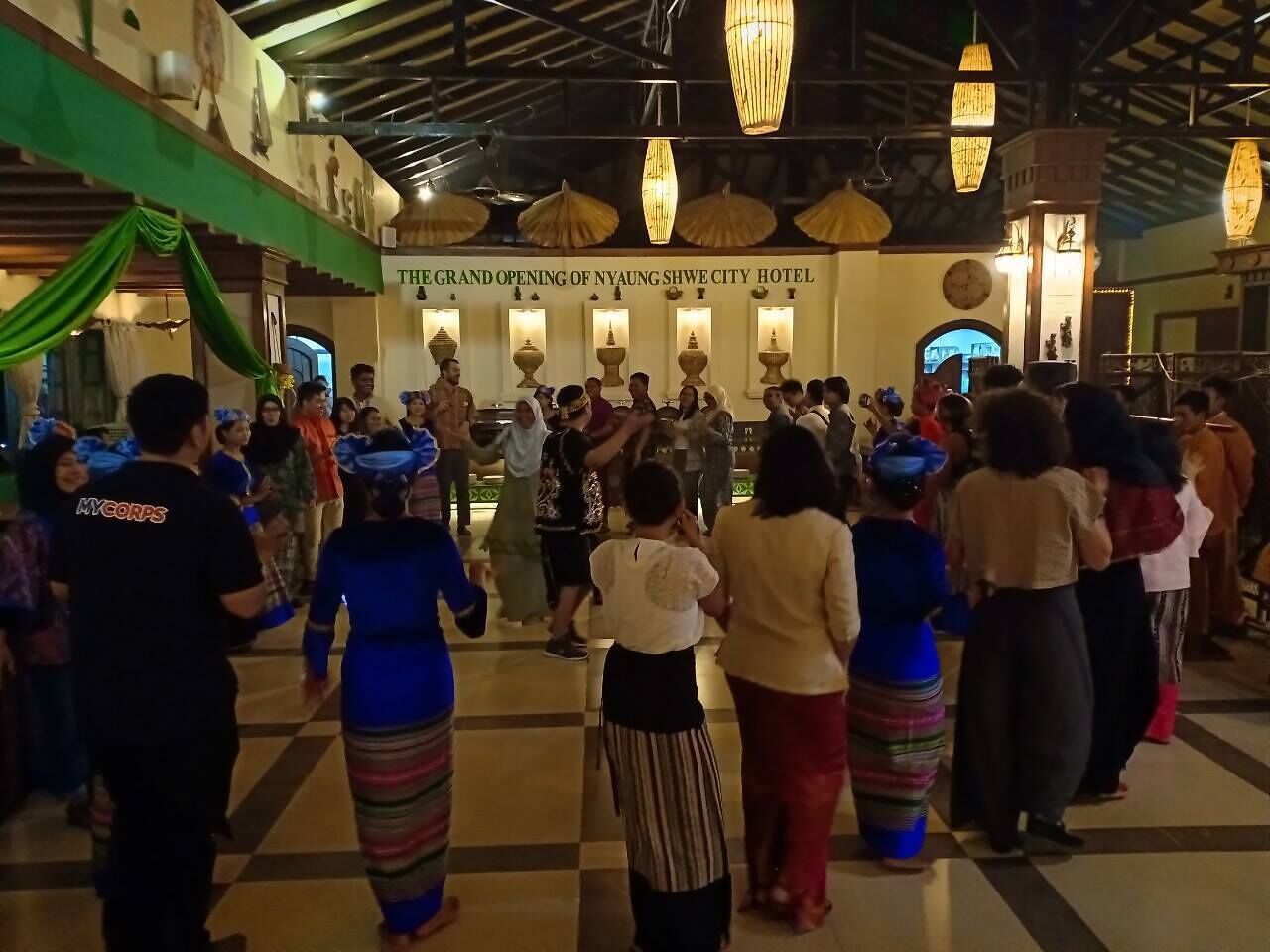 Evento de inauguración en un hotel con suelo a cuadros, decoración tradicional y mucha gente.