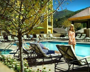 A pool area with lounge chairs, a yellow building, and a mountain in the background. - 2BR Residence at the Ritz-Carlton with Valley View by RedAwning - Save 20% on 7+ Nights! (Vail)