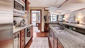 A spacious kitchen with granite countertops, wooden cabinets, and a large island with a sink. - Luxe 2BR+Den Ritz-Carlton Residence Quiet Location by RedAwning (Vail)