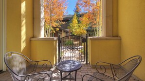 A balcony with two metal chairs and a small round table, overlooking a garden with autumn trees. - Luxe 2BR+Den Ritz-Carlton Residence Quiet Location by RedAwning (Vail)