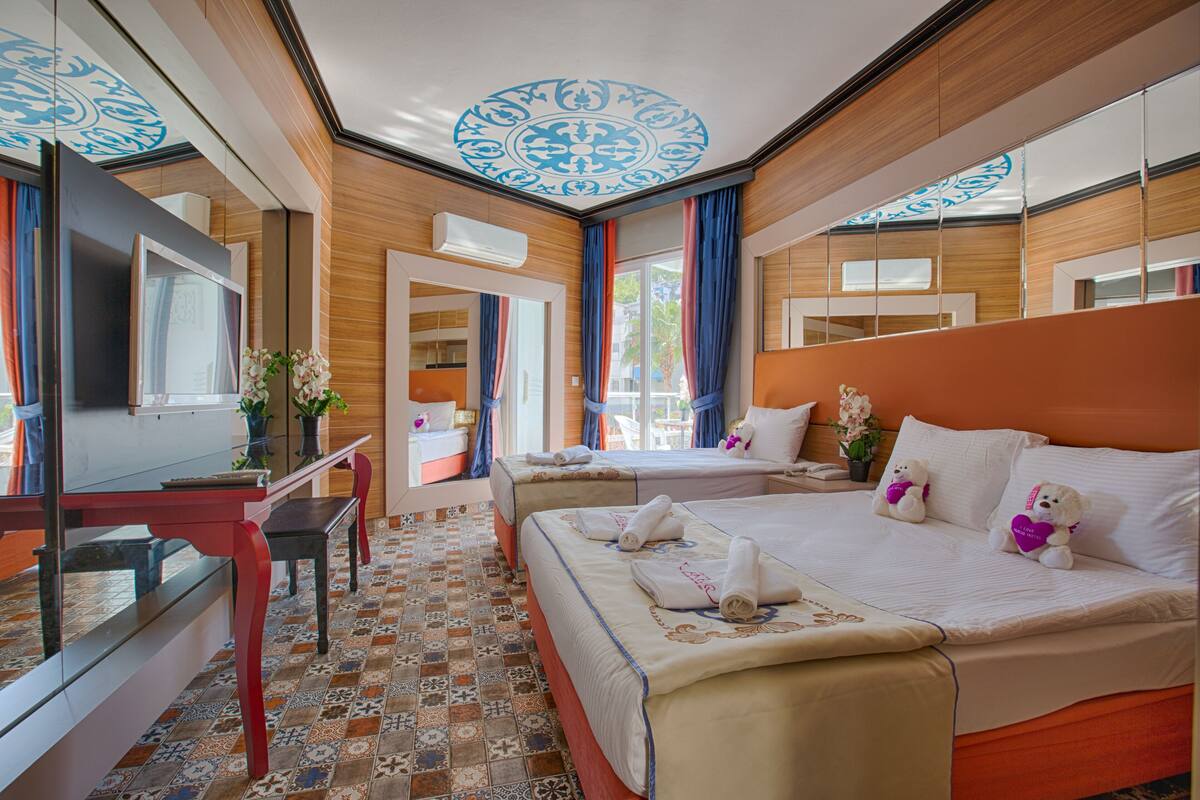 A hotel room with a large bed, a desk, a TV, and a bathroom visible through an open door.