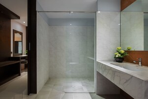 A modern bathroom with a glass shower enclosure, a marble sink, and a large mirror.