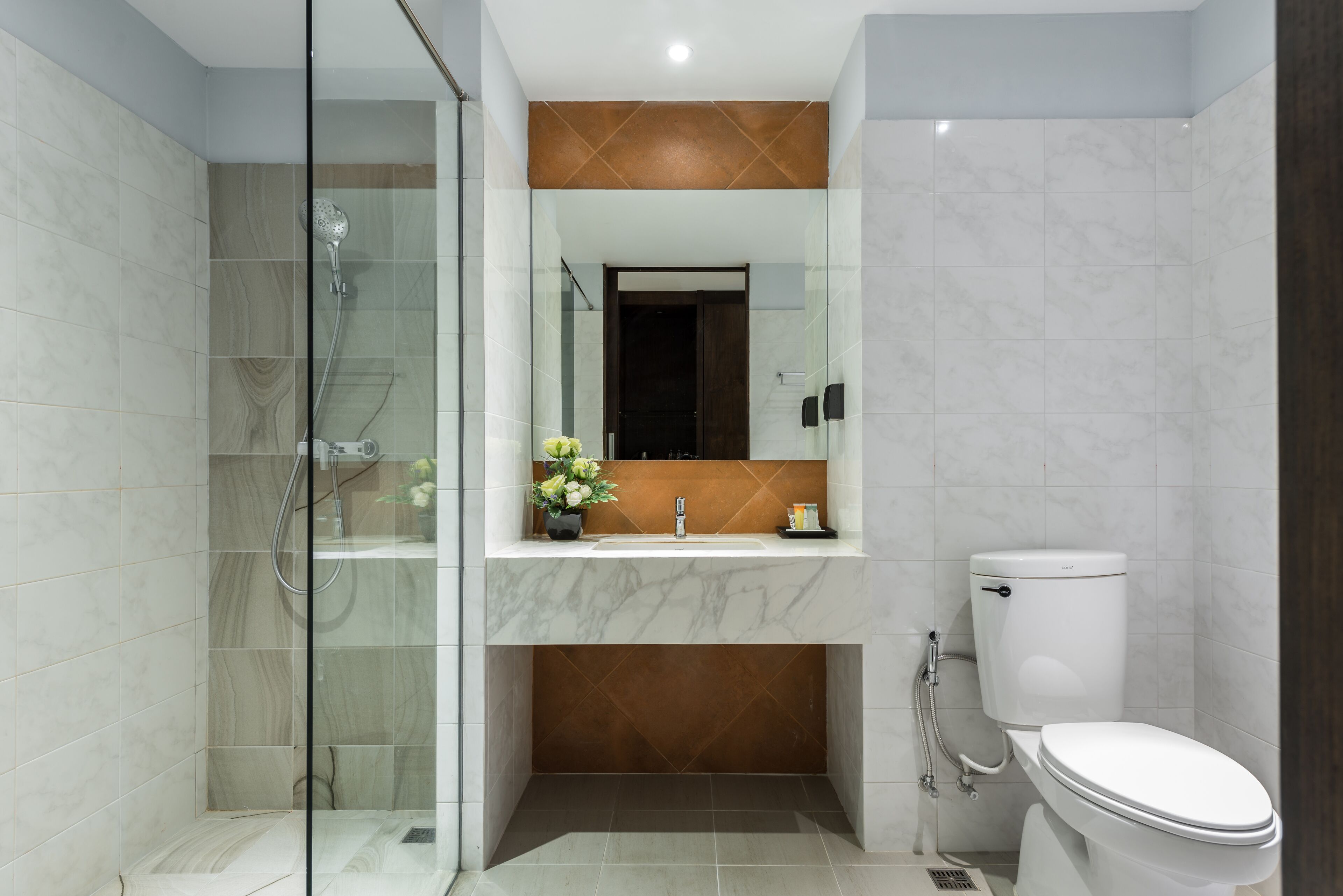 A modern bathroom with a glass-enclosed shower, a marble sink, and a toilet.