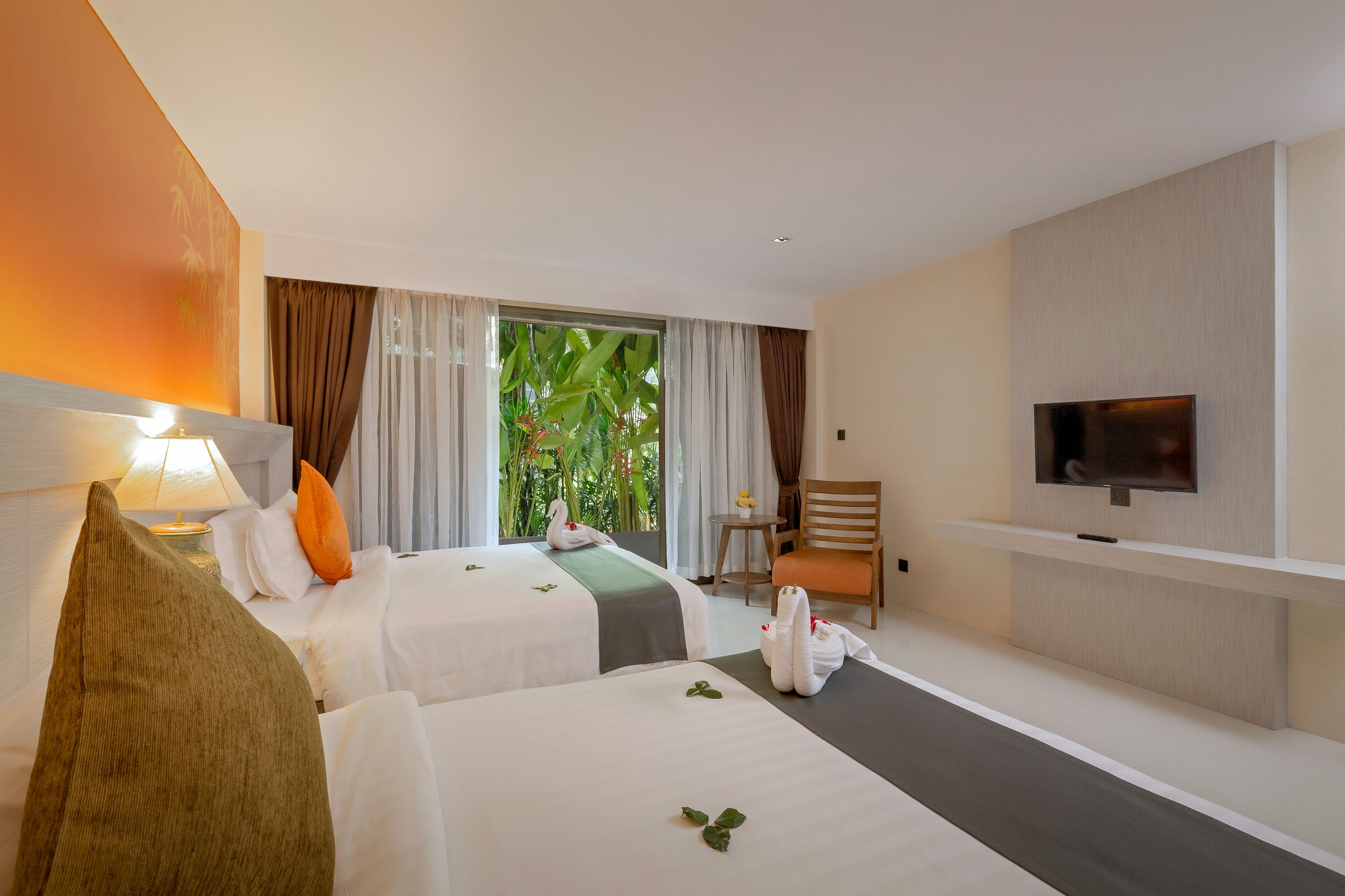 Ein Hotelzimmer mit zwei Betten, einem Fernseher, einem kleinen Tisch und einem Sessel.
