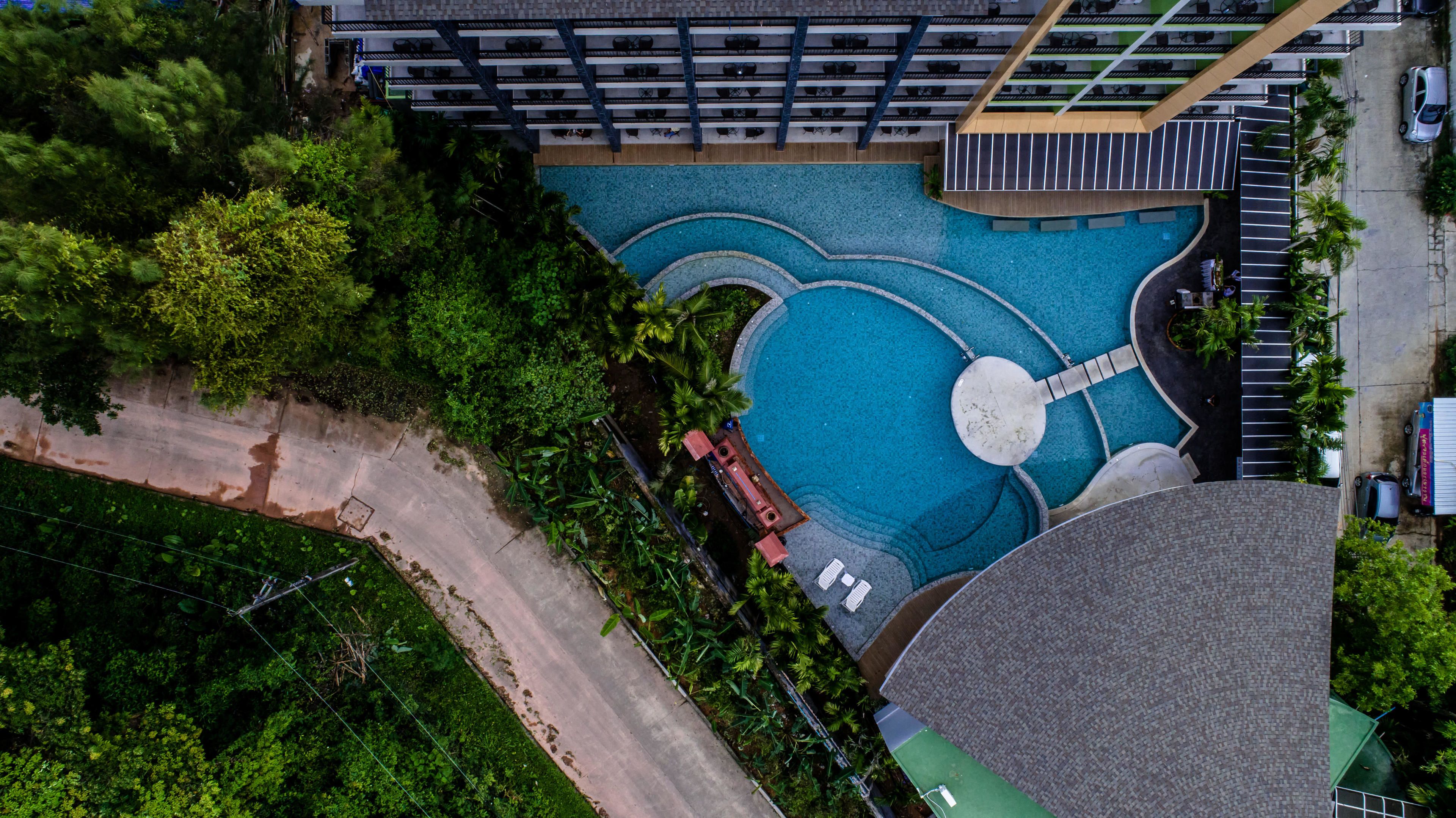 Vista aérea de un hotel con una gran piscina, varias terrazas y abundante vegetación alrededor de la propiedad.